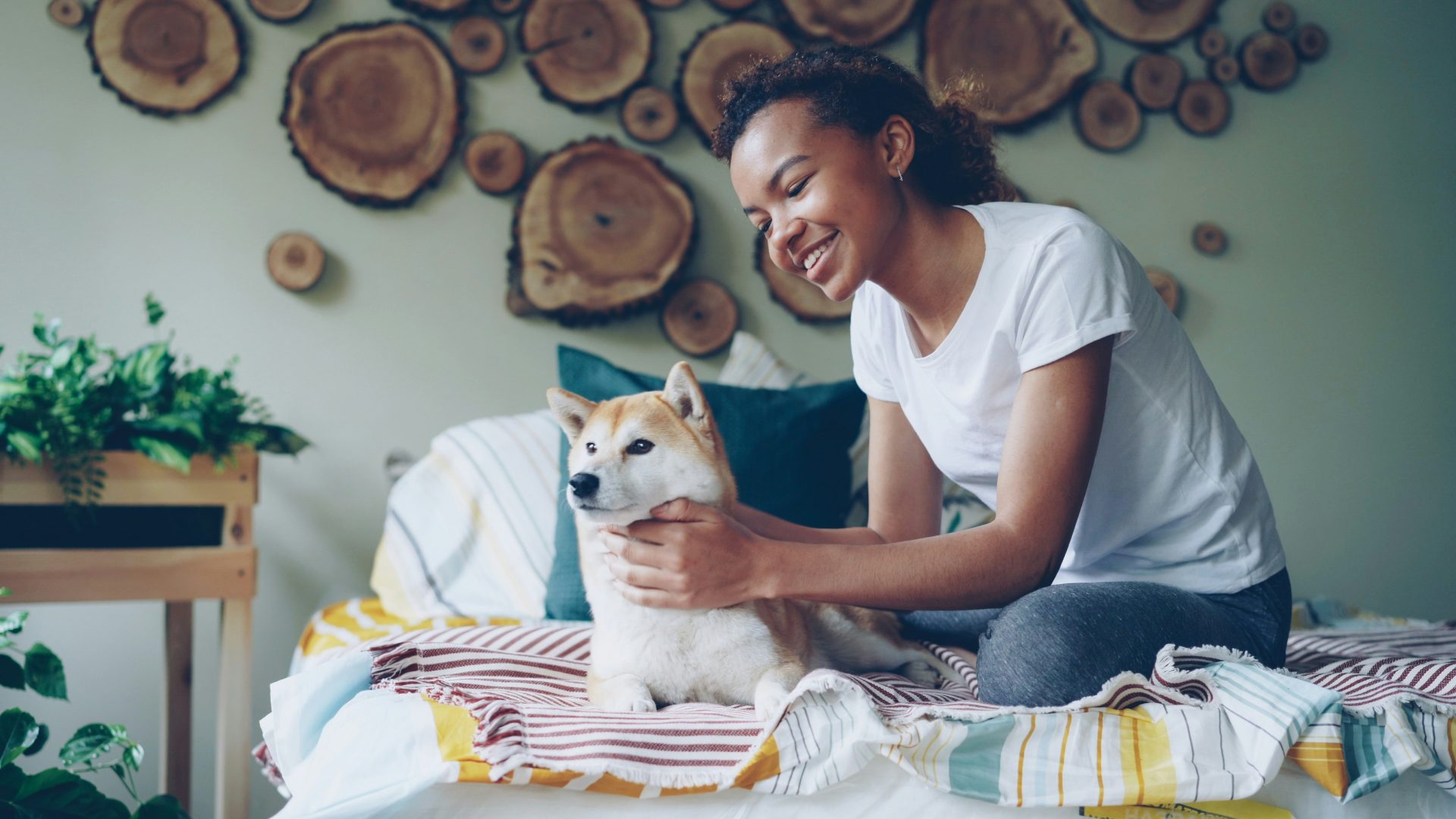 A woman pets her dog on the bed.